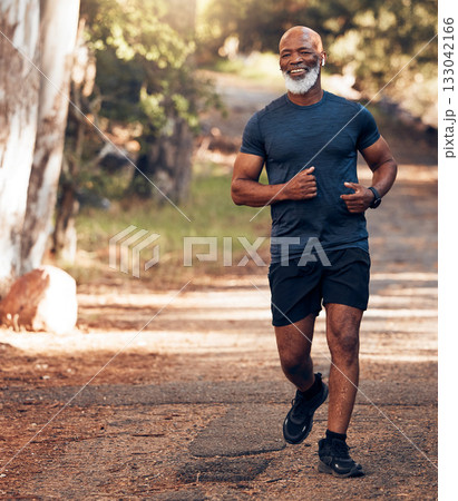 Music earphones, running and black man in nature for health, wellness and fitness. Radio, podcast and smile of happy senior athlete training, exercise and workout, cardio and jog outdoors at park. 133042166