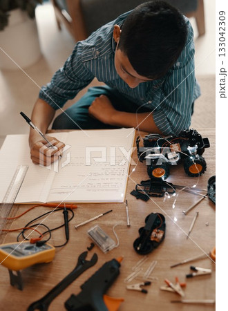 Education, writing in notebook and kid with robotics homework, homeschool and science for tech project. Taking notes, car robot and boy child with knowledge, learning and studying in house top view 133042309