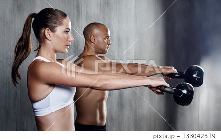 Fitness, people and weightlifting with kettlebell for arm workout or intense exercise together at the gym. Serious man and woman lifting weight for strong exercising, power or strength in training 133042319