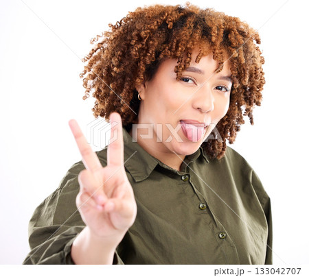 Tongue out, peace sign and portrait of a young black woman with funny hand sign in studio. Isolated, white background and gen z pose for social media with happiness and silly and funny hands gesture 133042707
