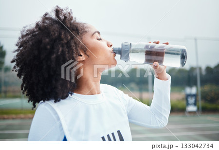 Sports, black woman and drinking water at court during training, workout and sport exercise outdoors. Fitness, thirsty and girl with bottle for wellness, hydration and recovery during practice Sports, black woman and drinking water at court during training, workout and sport exercise outdoors. Fitness, thirsty and girl with bottle for wellness, hydration and recovery during practice 133042734
