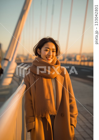 夕暮れの橋で微笑む女性|冬の都市風景に映えるナチュラルな笑顔と温もり 夕暮れの橋で微笑む女性|冬の都市風景に映えるナチュラルな笑顔と温もり 133042801