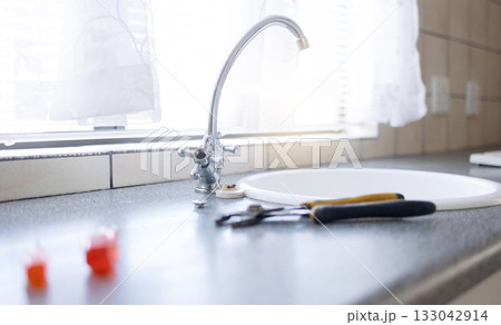 Faucet, tools and plumbing with maintenance in kitchen, repairs on sink with handyman trade and manual labor. Water tap, counter and home renovation with DIY, vocation skills and steel with service Faucet, tools and plumbing with maintenance in kitchen, repairs on sink with handyman trade and manual labor. Water tap, counter and home renovation with DIY, vocation skills and steel with service 133042914