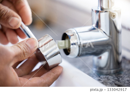 Plumber, hands and faucet, plumbing and maintenance with man, manual labour closeup and home renovation. Construction trade, handyman with kitchen or bathroom sink with hardware, pipe and DIY Plumber, hands and faucet, plumbing and maintenance with man, manual labour closeup and home renovation. Construction trade, handyman with kitchen or bathroom sink with hardware, pipe and DIY 133042917