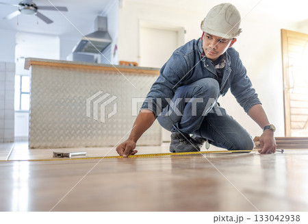 Man, carpenter and measure floor with tape, home interior and buildings maintenance. Builder, construction and handyman measuring flooring on ground, wood board house and property renovation tools 133042938
