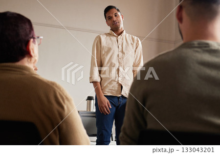 Support, man standing and introduction to group therapy, help, advice in sharing feelings and talking in session. Mental health, grief or depression, men and women listening to therapist and together 133043201