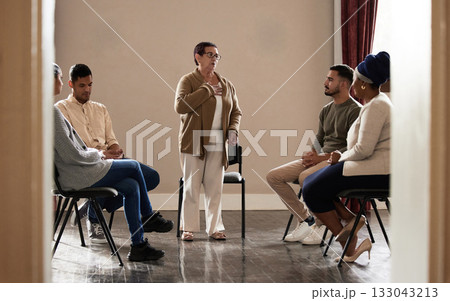 Support, old woman standing in group therapy and understanding, sharing feelings and talking in session. Mental health, grief or depression, men and women listening to therapist and sitting together. 133043213