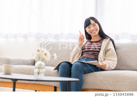 ソファーに座って雑誌を読んでいる若い女性 ソファーに座って雑誌を読んでいる若い女性 133043896