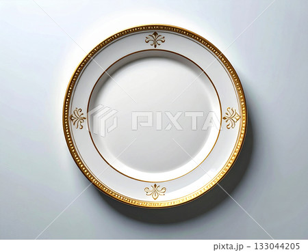 Formal elegance. Ceramic plate with a classic white and gold design on a white background. Porcelain kitchenware. Close-up. Top view. 133044205