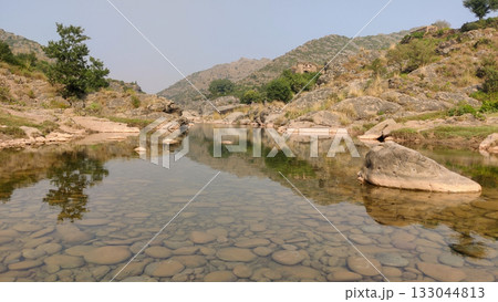 Mountain above clear water with visible stones below 133044813