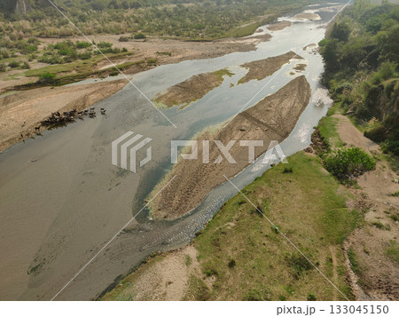 River landscape from above showing a herd of goats crossing together in shallow water River landscape from above showing a herd of goats crossing together in shallow water 133045150