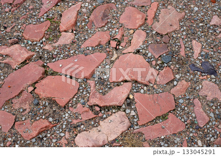 Old cobblestone pavement with uneven brown stones and patches of green grass. Ancient brick cobblestone tiles street with big stones Old cobblestone pavement with uneven brown stones and patches of green grass. Ancient brick cobblestone tiles street with big stones 133045291