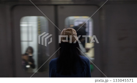 Blurred image of a woman standing on a train platform watching a train pass by. 133045571