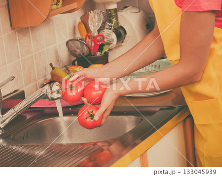 woman washing fresh vegetables in kitchen woman washing fresh vegetables in kitchen 133045939