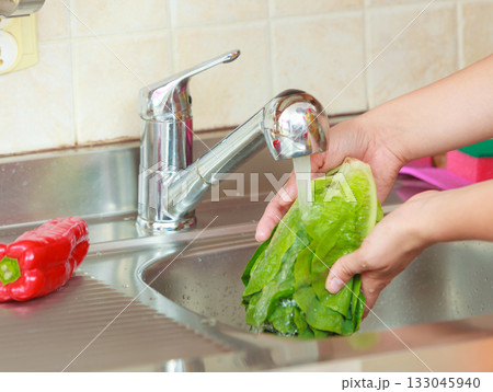 woman washing fresh vegetables in kitchen woman washing fresh vegetables in kitchen 133045940