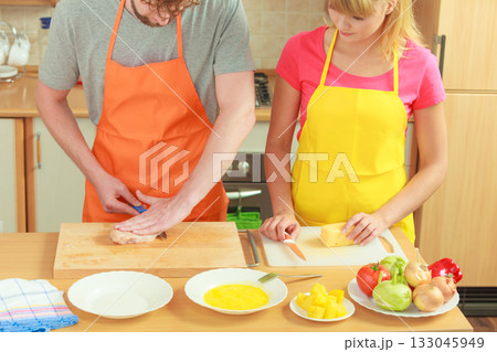 Man cutting meat on board. Couple in kitchen 133045949