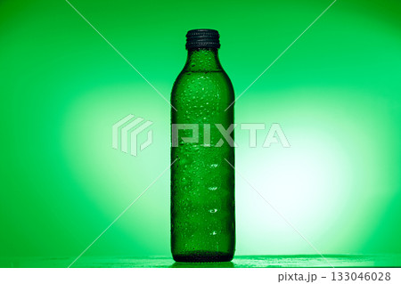 A green bottle of water is sitting on a table A green bottle of water is sitting on a table 133046028