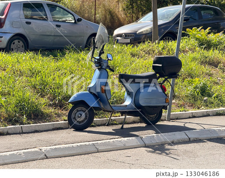Vintage blue scooter parked under sunlight. Urban transportation, simplicity, and retro everyday lifestyle. 133046186