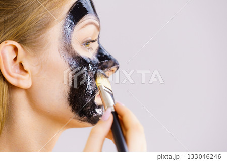 Woman applying black mask to skin face 133046246