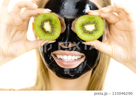 Girl black mask on face holds kiwi fruit Girl black mask on face holds kiwi fruit 133046290
