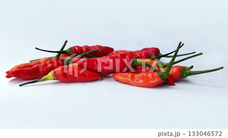 A bunch of bright red chilies with green stems arranged on a white background 133046572