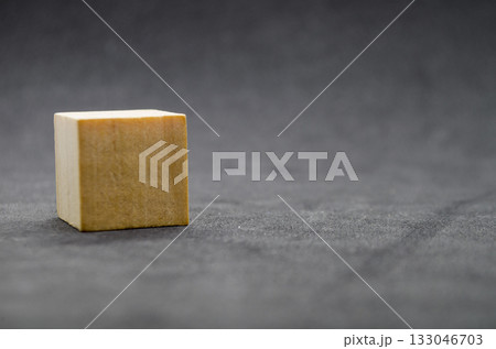 An isolated wooden cube on dark background with customizable space for text or ideas. Copy space concept. An isolated wooden cube on dark background with customizable space for text or ideas. Copy space concept. 133046703