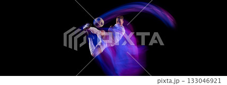 Soccer player performing overhead kick with dynamic neon trail on black background. Banner 133046921
