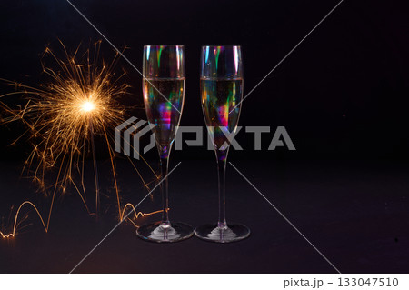 Sparkling Celebration. Two champagne glasses with bright sparklers against a dark background Sparkling Celebration. Two champagne glasses with bright sparklers against a dark background 133047510