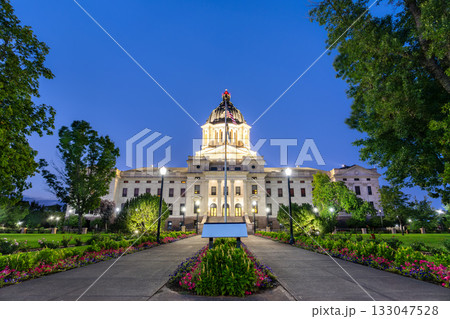 Illuminated South Dakota State Capitol building in Pierre at dusk. Walkway with flowers leads to the building, framed by trees under a clear blue sky Illuminated South Dakota State Capitol building in Pierre at dusk. Walkway with flowers leads to the building, framed by trees under a clear blue sky 133047528