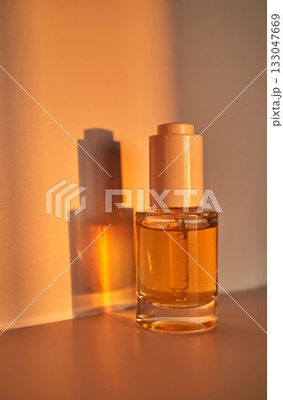 Skincare serum dropper bottle reflecting golden light 133047669