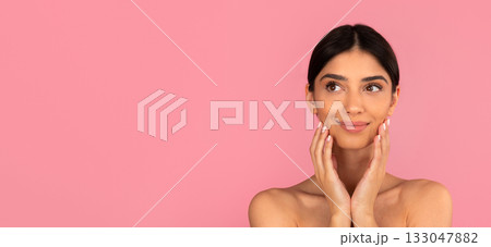 Beautiful young woman touching her face with soft hands and smiling slightly 133047882