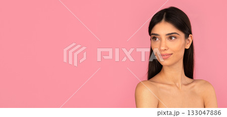 Smiling young woman with natural clean skin looking aside against pink background Smiling young woman with natural clean skin looking aside against pink background 133047886