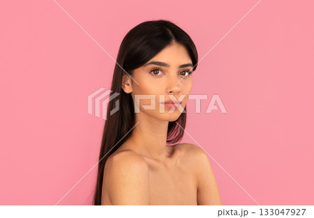 Beautiful woman with natural makeup and long hair posing against pink background 133047927