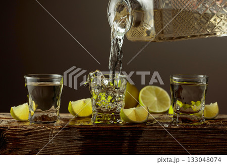 Gold tequila with salt and lime slices on a old wooden board. Gold tequila with salt and lime slices on a old wooden board. 133048074