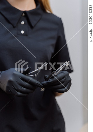 Gloved clinician holding sterile surgical instruments in clinic, closeup healthcare concept 133048358