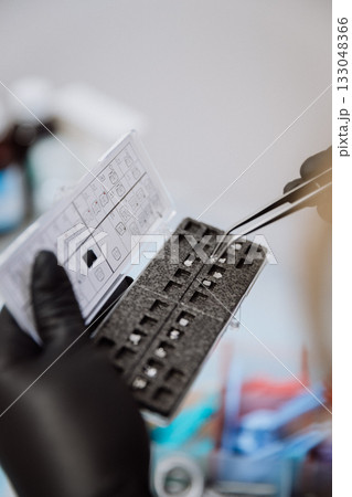 Orthodontic bracket kit with placement chart and tweezers, gloved hands, clinic closeup Orthodontic bracket kit with placement chart and tweezers, gloved hands, clinic closeup 133048366