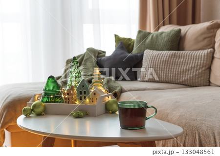 Cozy Holiday Living Room with Cup of Hot Beverage and Festive Tray with Ornaments Cozy Holiday Living Room with Cup of Hot Beverage and Festive Tray with Ornaments 133048561
