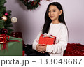 Little girl on floor with Christmas present, beaming with joy 133048687