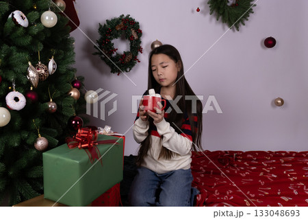 The girl is enjoying a hot drink from a red mug next to a Christmas tree The girl is enjoying a hot drink from a red mug next to a Christmas tree 133048693