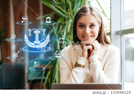Young professional woman smiling in a modern office environment with digital icons around her 133049129