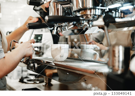 Barista preparing espresso in a bustling cafe during morning hours 133049141
