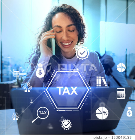 Professional woman talking on phone while working on taxes in modern office setting Professional woman talking on phone while working on taxes in modern office setting 133049155