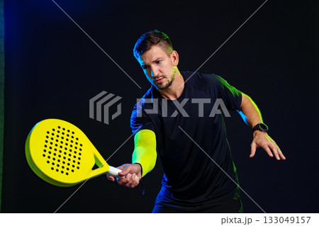 Professional player practicing padel in a studio with dramatic lighting 133049157