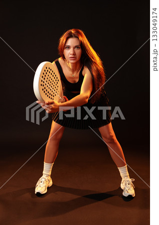 Young woman preparing to hit a ball in a dynamic indoor sports setting during twilight Young woman preparing to hit a ball in a dynamic indoor sports setting during twilight 133049174
