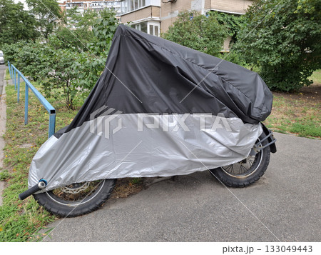 Black and gray cover on motorcycle parked in yard of house Black and gray cover on motorcycle parked in yard of house 133049443