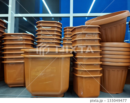 Plastic flower pots are sold at flower shop. Large brown flower pots on shelves 133049477