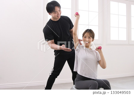 パーソナルトレーナーにトレーニングを受ける若い女性 133049503