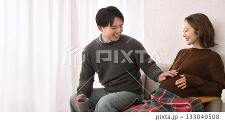 ソファに座ってくつろぐ若い夫婦　妊婦さん 133049508