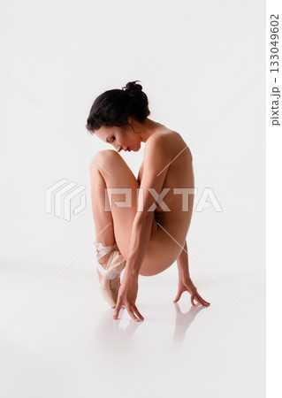 Ballerina in a graceful pose on pointe shoes against a minimalist backdrop Ballerina in a graceful pose on pointe shoes against a minimalist backdrop 133049602