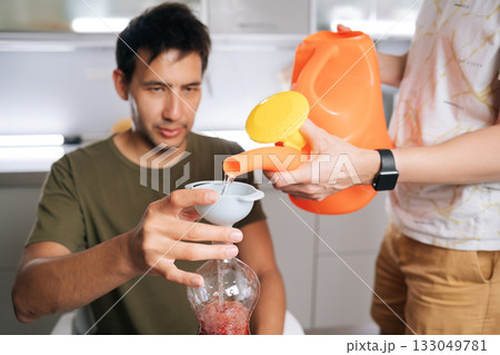 Focused biology students mixing fertilizer solution, using watering can, funnel and plastic bottles in laboratory setting, demonstrating precise scientific methodology. Concept of urban farming. Focused biology students mixing fertilizer solution, using watering can, funnel and plastic bottles in laboratory setting, demonstrating precise scientific methodology. Concept of urban farming. 133049781